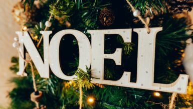 A wooden noel sign hanging from a christmas tree